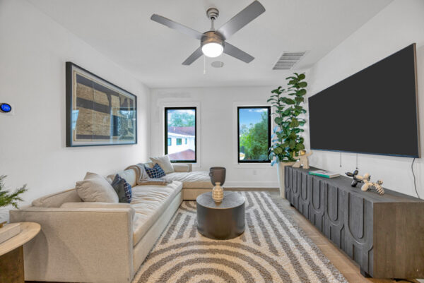Spacious loft area featuring high ceilings, large windows, and an open, airy design. The space is furnished with modern pieces, creating a stylish and versatile area ideal for relaxation or entertainment.