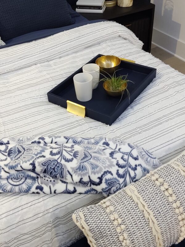 Coastal-inspired bedroom with a navy bed tray placed on a neatly made bed. The tray is styled with decorative items, adding a touch of elegance to the serene atmosphere. The room features light, airy tones, creating a peaceful and inviting retreat.