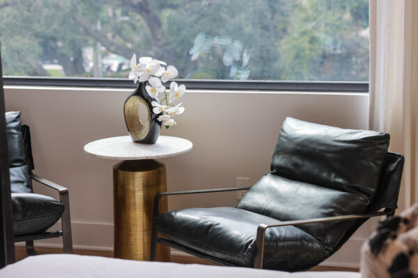 Spacious living room with a contemporary design, featuring a comfortable sofa, decorative throw pillows, and a modern coffee table. The open layout flows into the adjacent dining room, creating a seamless connection between the two spaces. Large windows bring in ample natural light, highlighting the neutral color palette and elegant decor. The dining area is furnished with a stylish table and chairs, creating a cohesive and inviting atmosphere throughout the room.
